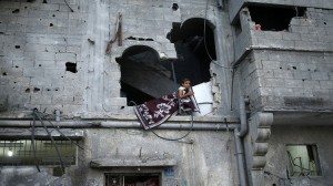 Palestinian girl looks out through her family's damaged house, which witnesses said was shelled by Israel during the seven-week offensive, in the devastated area of the east of Gaza City